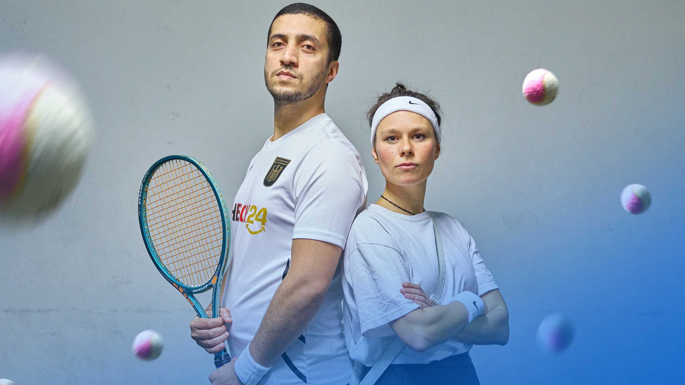 Extrawurst, Foto: Martin Patze ein Mann und eine Frau in Tenniskleidung stehen Rücken an Rücken und schauen in die Kamera
