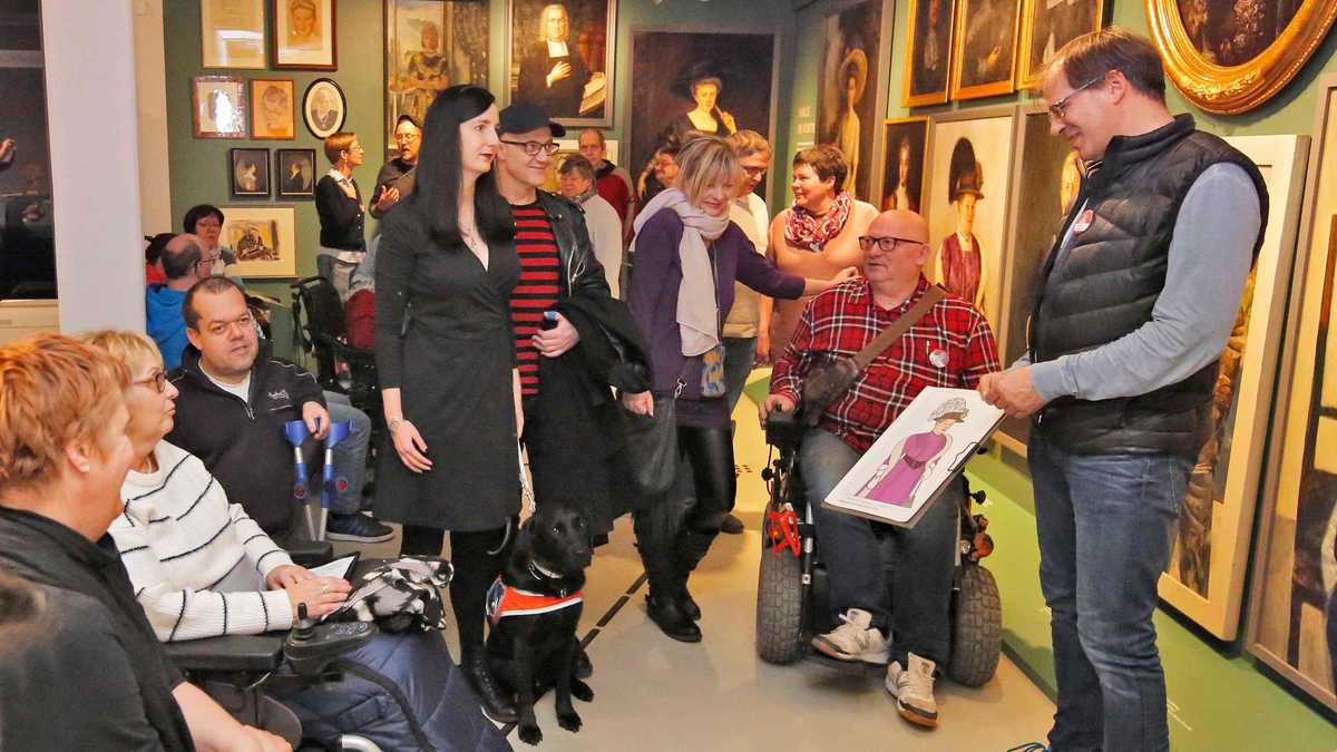 Führungen ein Ausstellungsraum mit vielen Menschen, die eine Führung verfolgen. Sie betrachten ein Bild, dass von der Führung gezeigt wird