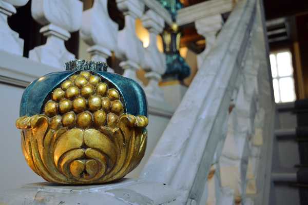 geschnitzter Granatapfel in Türkis und Gold als Schmuckelement des Treppengeländers